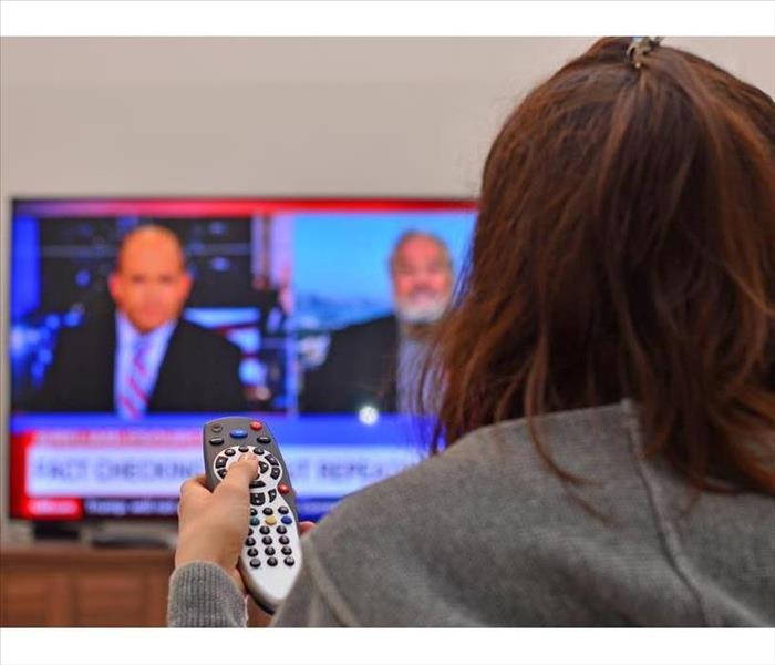 Woman watching TV and using remote controller